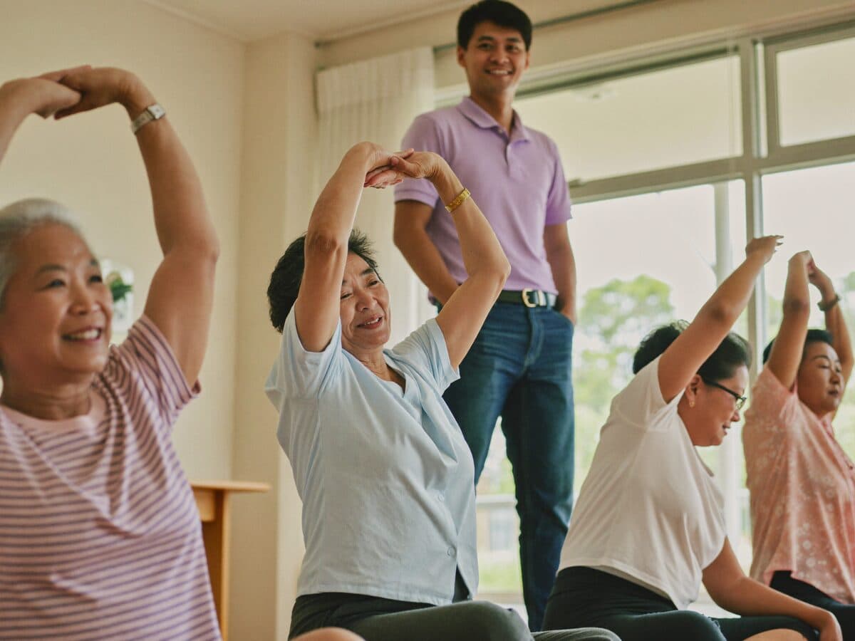 Seniors at MS Care doing gentle seated stretching and movement exercises with a facilitator during the MOVE hour.